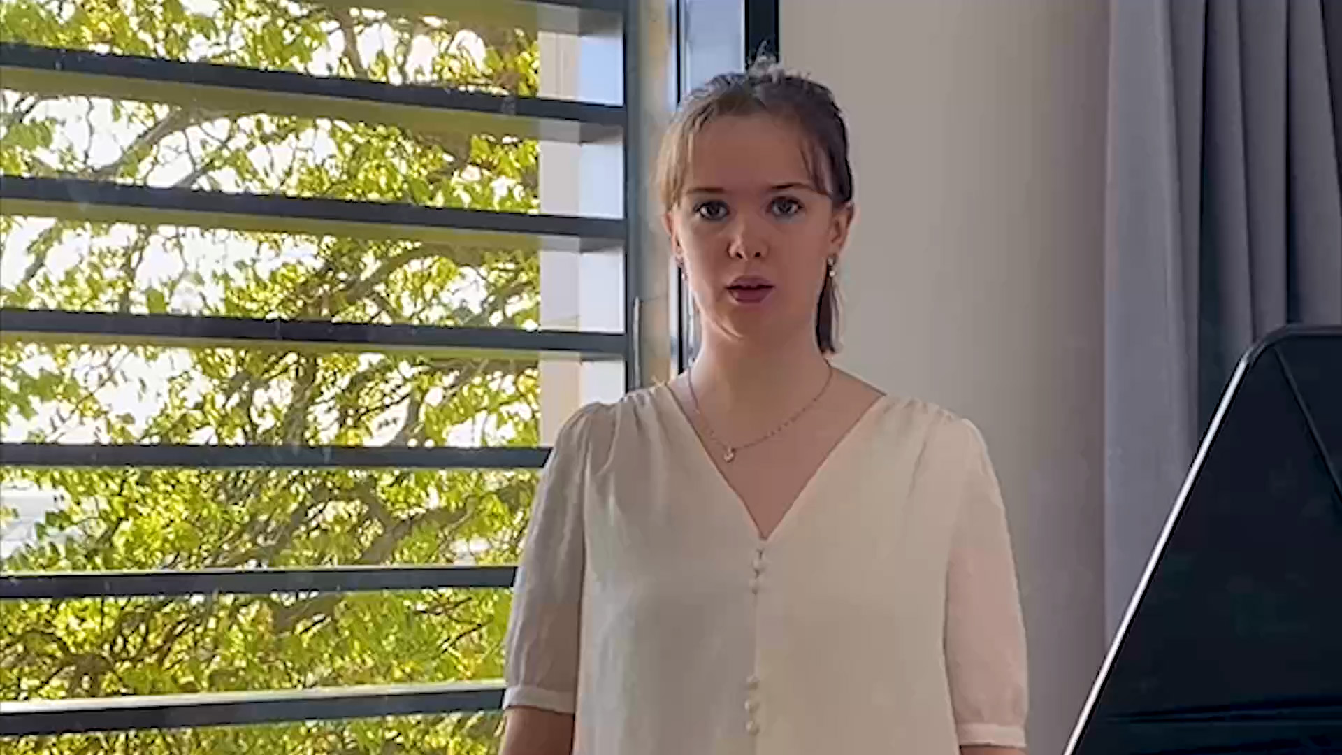 Emily Kemp singing beside window